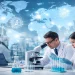 Global life sciences research laboratory with scientists analyzing samples under a microscope, world map background, and ScholarLink watermark representing international PhD research destinations.
